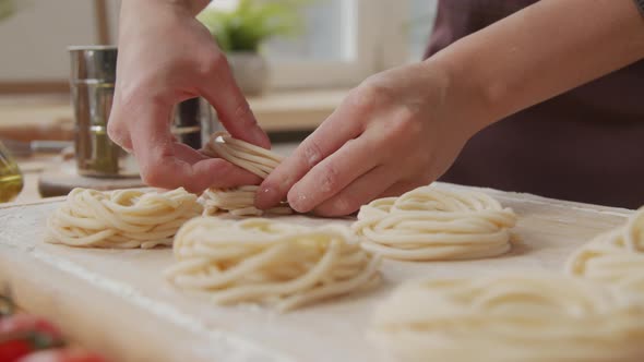 Hands of Woman Forming Fresh Pasta into Nests