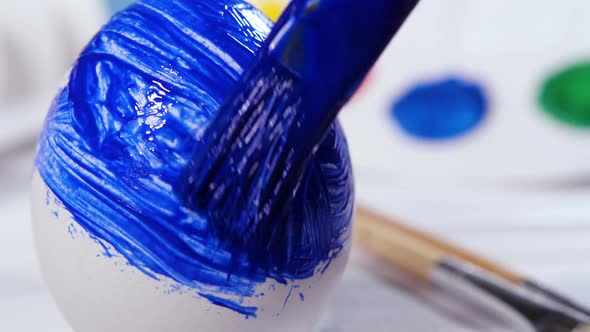 Painting Easter Eggs with a Blue Brush Preparation for Spring Holiday Religious Celebration Art