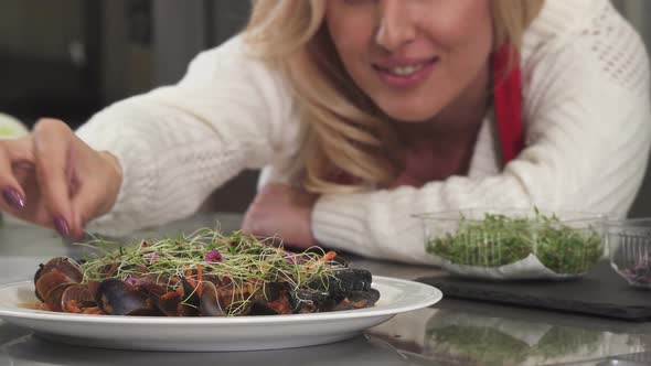 Beautiful Woman Decorating Mussels Dish on a Plate Preparing Food at Home