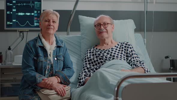 Portrait of Elder Patient and Wife Sitting in Hospital Ward