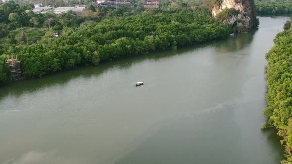 single lonely Thai longtail boat floating on a river surrounded by green mangrove forests in Krabi T