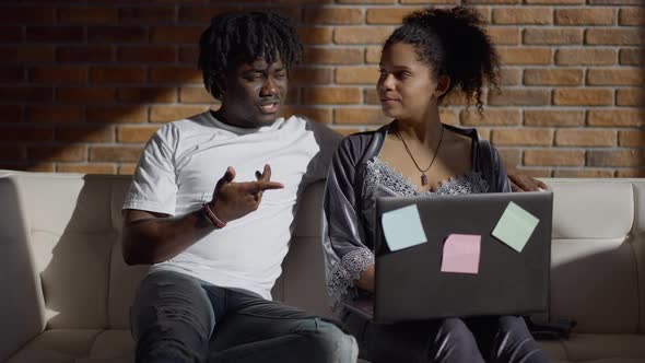 Confident Young Couple Sitting in Sunny Home Office on Comfortable Couch Talking Surfing Internet