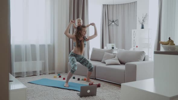 Mom Trains with Her Daughter at Home and Looks at the Laptop