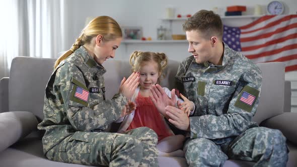 Cheerful US Military Couple Playing Pat-A-Cake With Little Daughter at Home