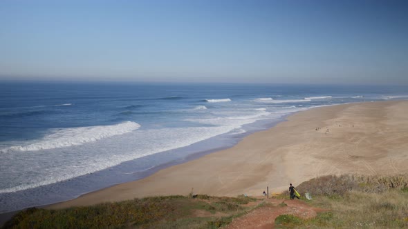 Surfer heading down the cliff in Praia do Norte, Nazare