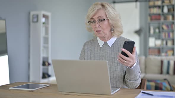 Old Woman Using Smart Phone and Working on Laptop