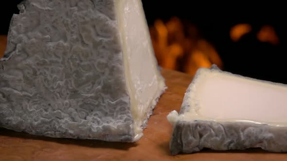 Piece of the Pyramid Valencay Cheese Is Falling on a Wooden Board