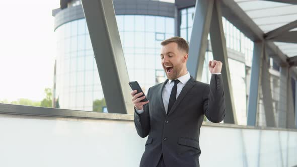 A Happy Bearded Startup Bussinesman Reading Good News in Smartphone