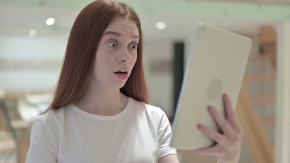 Portrait of Redhead Young Woman Reacting To Loss on Tablet