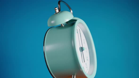 Turquoise Retro Alarm Clock Rings at 6 Am and Rotates Slowly on a Blue Background