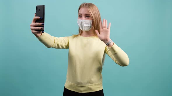 Young Girl with Medical Mask on Face Greets Friends During Online Conversation
