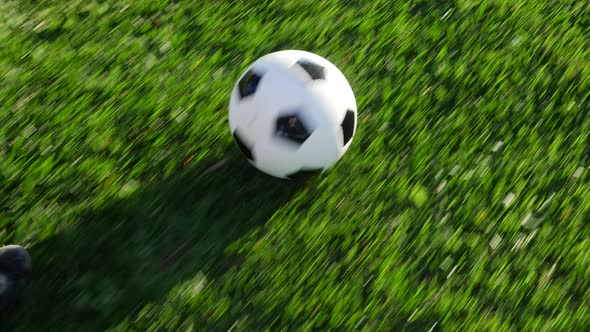 Close up on the cleats of a soccer player running with a football dribbling up the grass field to sc