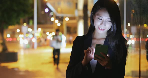 Business woman looking at mobile phone at night 