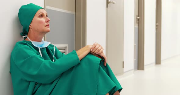 Tensed female surgeon sitting in corridor