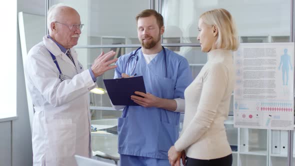 Senior Doctor Speaking with Assistant and Female Patient