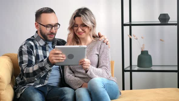 Pleasant Couple Hugging Talking Use Tablet Pc Together Relaxing on Couch