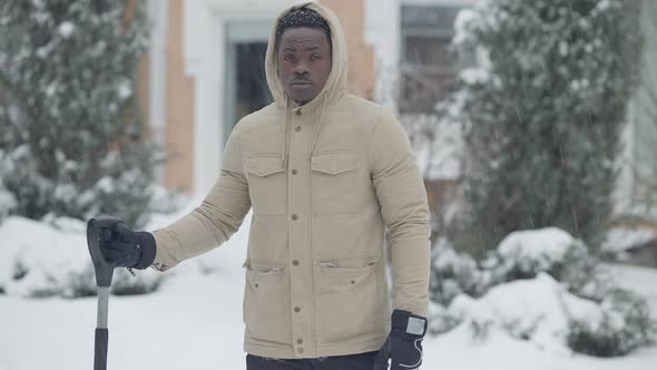 Middle Shot of Confident African American Man Standing with Shovel in Snowfall