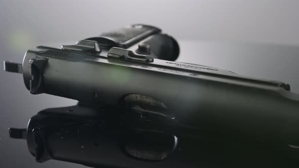 Gun Control. Studio shot of a 9mm gun rotating on a reflective surface