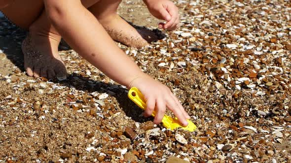 Little tanned girl playing with sand on the beach ocean sea. Summer vacation, travel.