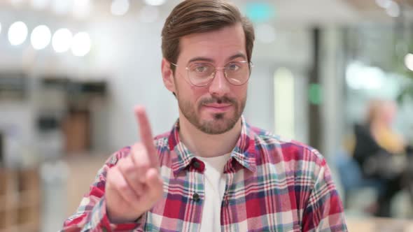 Portrait of Serious Male Designer Saying No By Finger Sign