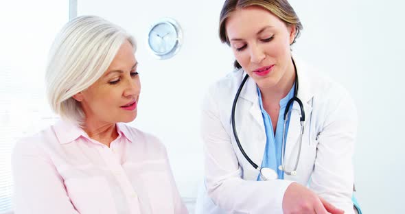 Female doctor and colleague discussing over digital tablet