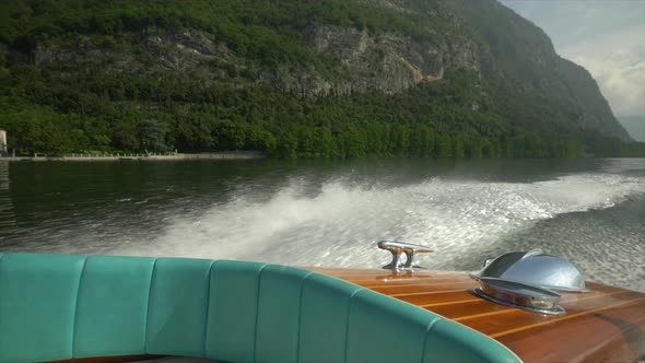 Water spray comes from a classic luxury wooden runabout boat on an Italian lake.