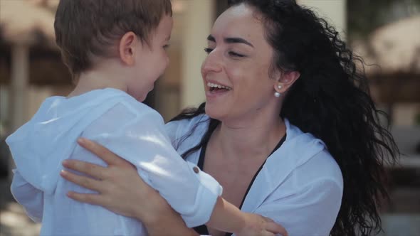 Happy Mother Hugging Her Child on the Coast. Cute Kid Kisses His Mom and Gently Hugs. Concept Mom