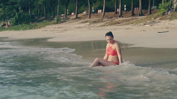 Woman in Swimsuit Sits in Ocean Waves in Evening Slow Motion