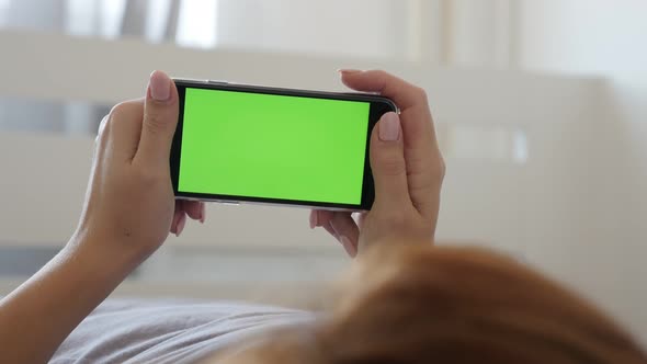 Woman in bed with modern green screen smart phone  4K 2160p 30fps UltraHD video - Female holds green