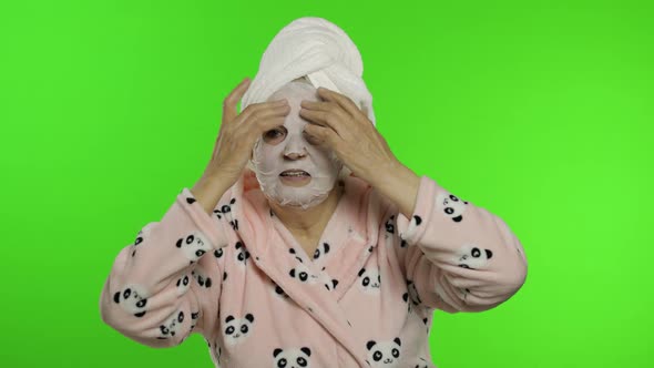 Elderly Grandmother After Shower. Old Woman Applying Cosmetic Fabric Face Mask