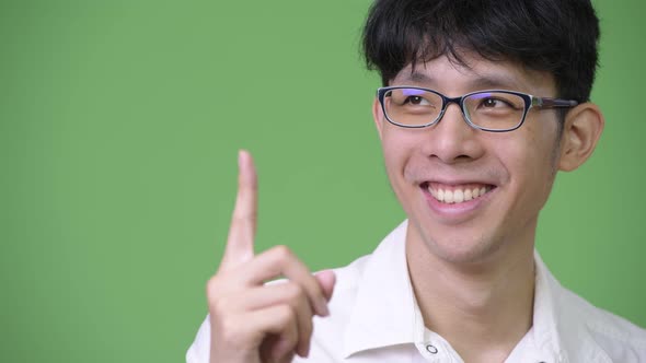 Young Happy Asian Businessman Pointing Up and Thinking