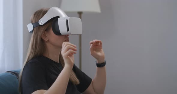 Young Woman with HMDdisplay on Head Is Viewing Photos in Virtual Reality Gesticulating Hands for