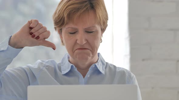 Thumbs Down By Old Woman Looking at Camera at Work