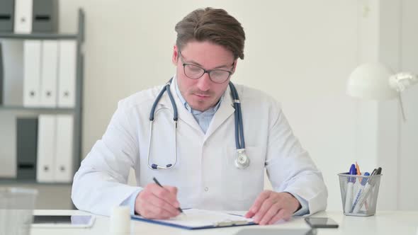 Middle Aged Male Doctor Writing on Paper 