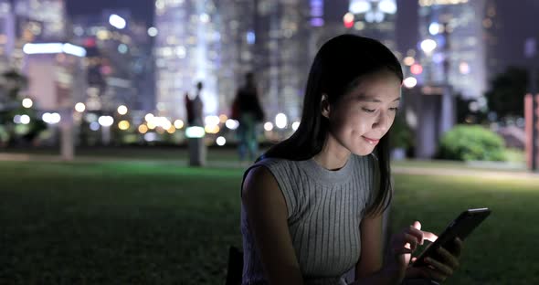 Woman using mobile phone in city at night 