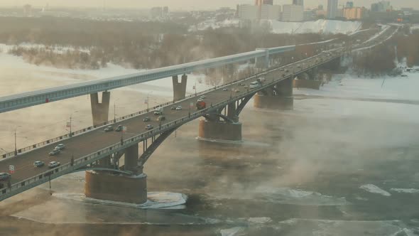 In a Winter City, an Impressive Bridge Rises Above an Ice-covered Steamy River.