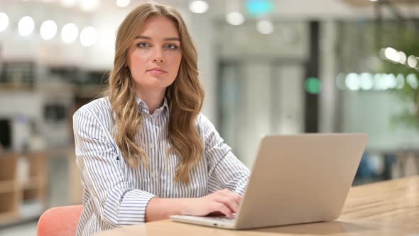 Businesswoman with Laptop Looking at Camera 