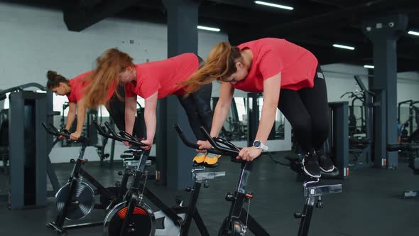 Athletic Women Group Riding on Spinning Stationary Bike Training Routine in Gym Weight Loss Indoors