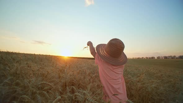 A Little Boy in a Hat Runs Through a Wheat Field