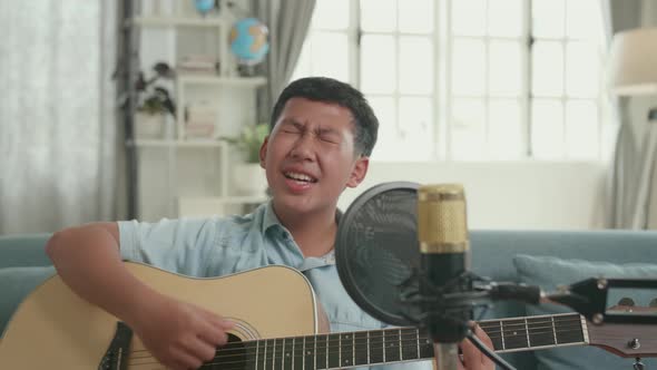 Asian Boy Playing Guitar And Sing A Song At Home