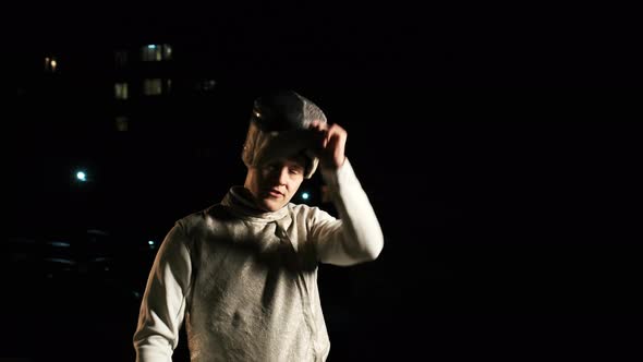 Young Fencer In Fencing Suit Removes Protective Helmet From His Head.