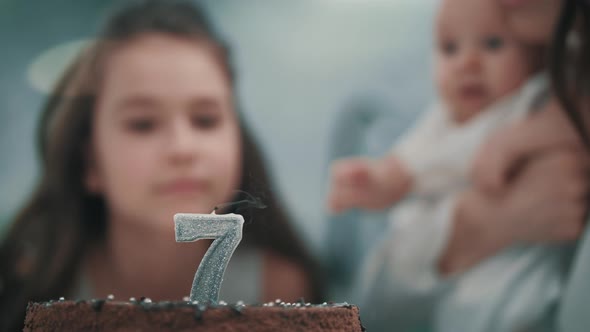 Girl Blowing Candle on Birthday Cake at Family Party