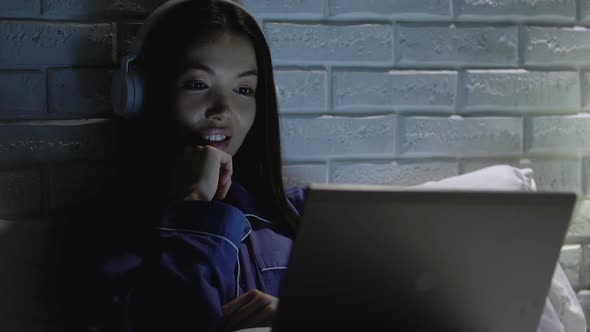 Smiling Female in Headphones Watching Comedy Show on Laptop at Night, Relax
