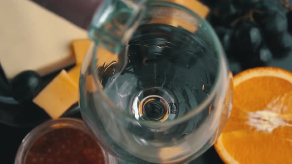 Rose Wine is Poured Into a Glass With Snacks in Slow Mo