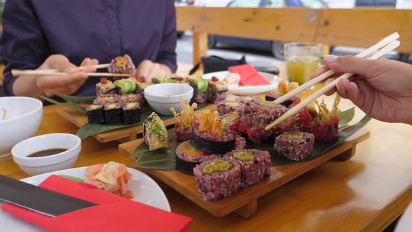 Two People Eating Delicious Vegan Sushi Rolls, Dipping Into Soy Sauce at First. Healthy Vegan Street