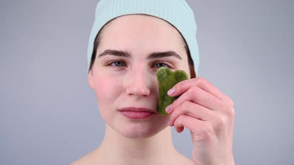 Closeup Portrait of a Young Woman Massaging Her Face with a Gouache Scraper