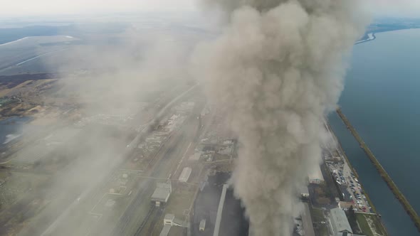 Aerial view of coal power plant high pipes with black smoke moving up polluting atmosphere.