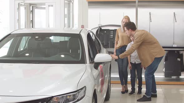 Young Beautiful Couple with Child Choosing Their First Auto