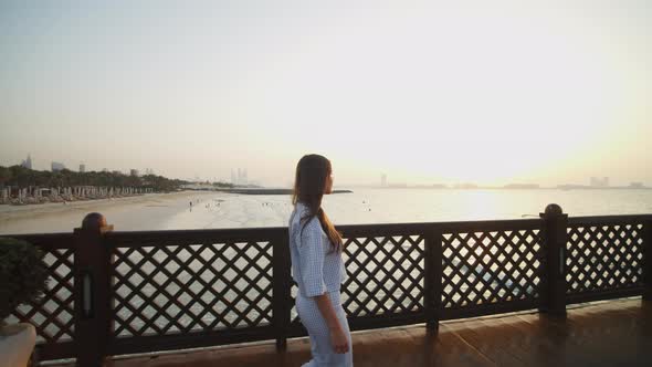 Woman Walking on Ocean Pier in Dubai During Sunset