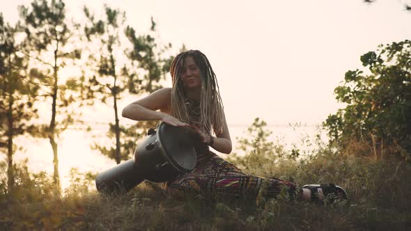 Beautiful Young Hippie Woman with Dreadlocks Playing on Djembe